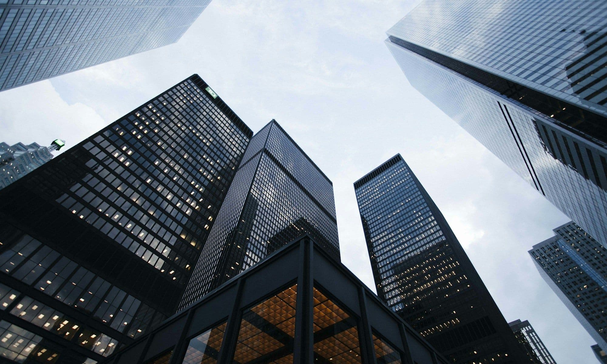 Dark skyscraper facades seen from below, ordered vertical lines converging upward